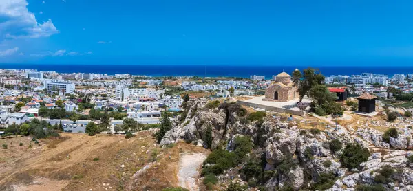 Kıbrıs Rum Kesimi 'nin Ayia Napa kentindeki kayalık bir tepenin üzerindeki St. Elias Kilisesi' nin hava manzarasında beyazlatılmış binalar, tatil beldeleri ve arka planda Akdeniz.