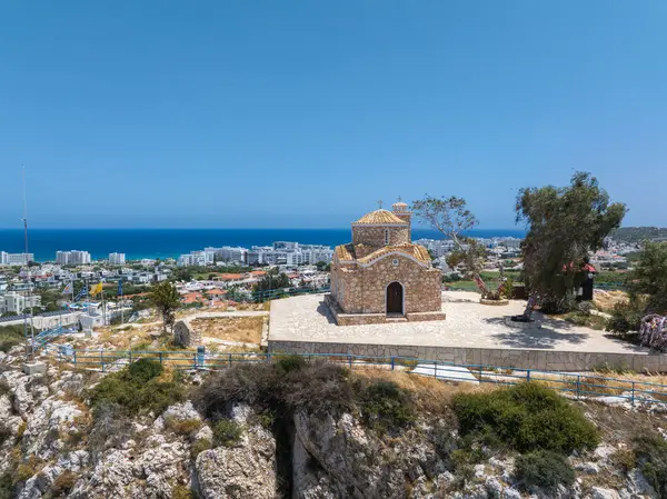 St. Elias Kilisesi kaldırımlı bir avlusu, ağaçları ve korkulukları olan bir tepede Ayia Napa, tatil köyleri ve Akdeniz manzarası sunar..