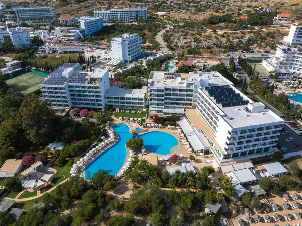 Kıbrıs Rum Kesimi 'nin Ayia Napa kentindeki benzersiz havuzlar, güneş panelleri, yemyeşil alanlar, güneş panelli çatılar ve Akdeniz çevresiyle modern bir tatil beldesinin havadan görünüşü.