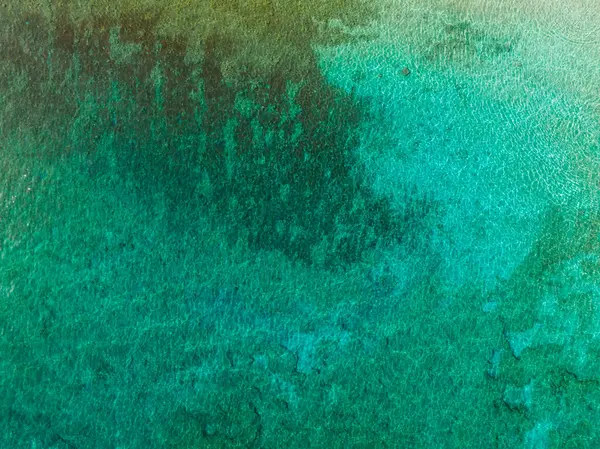 Kıbrıs Rum Kesimi 'nin Ayia Napa kenti yakınlarındaki temiz turkuaz suların havadan görünüşü, görünür sualtı dokuları ve desenleriyle yeşil ve mavi eğimlerini gösteriyor.