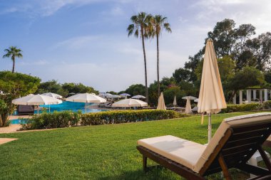 Kıbrıs 'ta, beyaz şemsiyeli, güneşli, yemyeşil, uzun palmiye ağaçları ve açık mavi gökyüzünün yer aldığı sakin bir tatil köyü..