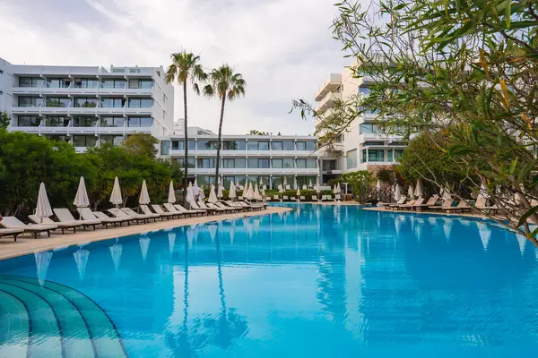 Kıbrıs 'ta geniş bir havuzu, beyaz şemsiyeleri, şezlongları, uzun palmiye ağaçları ve bereketli yeşillikleri olan modern bir otel tesisi huzur verici bir ortam yaratıyor..