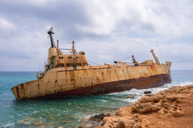 Edro III 'ün enkazı, Kıbrıs' ın Paphos kentinin kayalık kıyı şeridine yakın, turkuaz suları ve parçalı bulutlu gökyüzü ile çevrili, dramatik bir manzara yaratıyor..