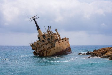 Edro III 'ün gemi enkazı, parçalı bulutlu bir gökyüzünün altında durgun turkuaz sularla çevrili Kıbrıs' ın kayalık kıyıları yakınında dinleniyor..