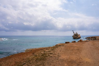 Edro III 'ün enkazı Kıbrıs yakınlarındaki turkuaz sulara dayanır, engebeli bir toprak yolu ve bulutlu bir gökyüzünün altında kayalık bir arazisi vardır..