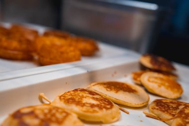 Beyaz servis tepsisine serpiştirilmiş kahverengi krepler. Çıtır çıtır dokular görünür. Arka plan hafifçe bulanık, krepleri vurguluyor..