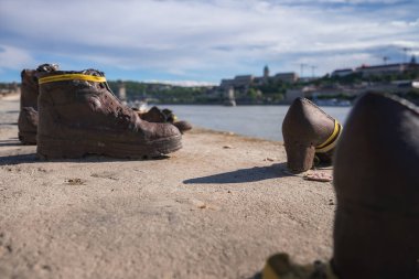 Budapeşte, Macaristan 'daki Tuna kıyısındaki Yahudi Soykırımı Anıtı' nda ayakkabılar, nehir kıyısı boyunca bronz ayakkabılar, Buda Kalesi ve arka planda Zincir Köprü.