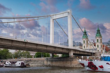 Budapeşte 'deki Elisabeth Köprüsü manzarası Tuna Nehri' ni kaplıyor. St. Anne 'in yeşil kuleleri ve kırmızı kurdeleli bir teknesi var..