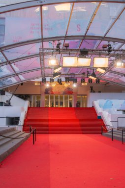 Fransa 'nın Cannes kentindeki Palais des Festivals' teki ikonik kırmızı halı ve merdivenler, şeffaf bir tepe örtüsü, aydınlatma platformları ve festival afişleriyle.