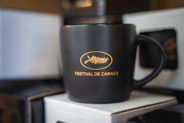Cannes Festivali 'nin altın palmiye yaprağı logosunun yer aldığı siyah seramik bir kupa, perakende veya hatıra olarak beyaz bir kutuya yerleştirilmiş..