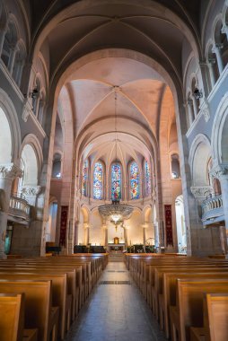 Görüntü Fransa 'nın Cannes kentindeki büyük katedrali gösteriyor. Yüksek kubbeli tavanları, yanan bir sunağı, süslü bir avizesi, vitray pencereleri ve ahşap sıraları var..