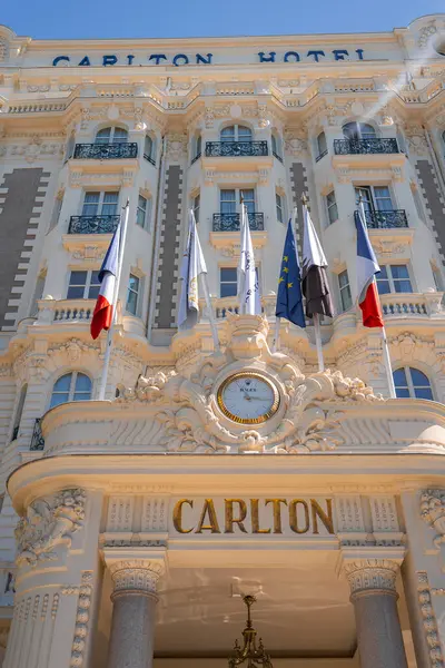 Fransa 'nın Cannes kentindeki Carlton Oteli' nde dekoratif sütunlar, balkonlar, merkezi bir saat ve belirgin bir şekilde sergilenen bayraklar yer alıyor..
