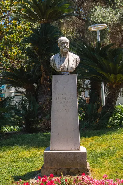Mösyö Le Fol Gouraud 'nun Cannes, Fransa' da bir bahçede, taştan bir heykel üzerinde büstü. Palmiye ağaçları, çiçek açan bitkiler ve bir sokak lambası ile çevrili..