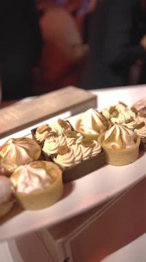 Cannes Festivali sırasında yatta tatlıları kapatıyoruz. Konuklar arka planda resmi kıyafetlerle kaynaştıkça kremalı ve fındıklı hamur işleri sergileniyor.