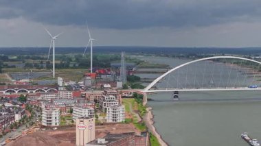 Hollanda, Nijmegen 'deki De Oversteek köprüsünün hava manzarası, Waal Nehri' ndeki tekneler, yeşil manzaralar, kumlu bankalar ve elektrik hatları..