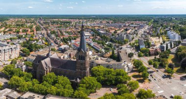 Hollanda 'nın Eindhoven kentinin havadan görünüşü, yeşillik ve kentsel mimari karışımı ile çevrili ikiz kuleleriyle St. Catherine Kilisesi' ni vurguluyor..
