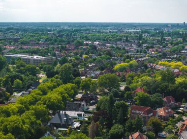 Eindhoven, Hollanda 'nın havadan görünüşü, kırmızı çatılı evler, modern binalar, yemyeşil, düz arazi ve uzak sanayi yapıları sergileniyor.