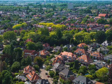 Hollanda, Eindhoven 'ın hava görüntüsü, kırmızı fayanslı evleri, ağaç kaplı caddeleri, şehir ortasındaki yükselen binaları ve geniş yeşil alanları gösteriyor..