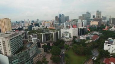 Singapur 'un gökdelenleri, SMU kampüsü, yeşil alanlar, trafiği olan yollar ve hareketli bir günde bulutlu bir gökyüzü içeren şehir manzarası..