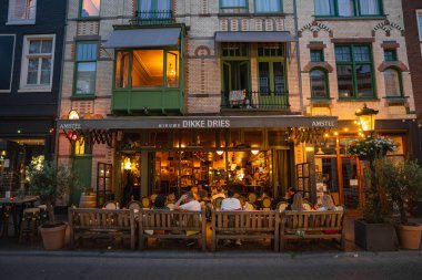 Utrecht, Hollanda 'da büyüleyici bir cadde, Nieuwe Dikke Dries restoranı, klasik Hollanda mimarisi, açık hava oturma ve asılı çiçeklerin yer aldığı.