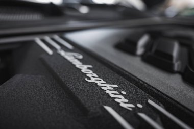 Lamborghini Urus 'un dokulu siyah motor kapağında beyaz Lamborghini logosu bulunur. Keskin çizgiler ve karmaşık detaylar odak noktasında vurgulanır.