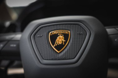 Lamborghini Urus 'un direksiyon simidinin detaylı görüntüsü, siyah bir arkaplanda dokulu boğa amblemi sergileniyor..