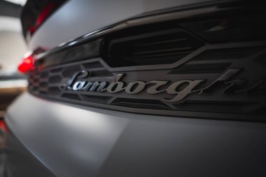 Lamborghini Urus 'un arka kısmının yakın görüntüsünde siyah ızgara, beyaz vücut ve parlak kırmızı kuyruk lambası var..