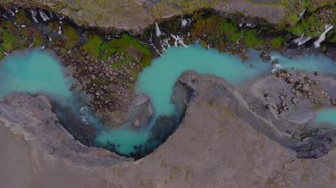 İzlanda 'daki Sigoldugljufur Kanyonu' nun havadan görünüşü, turkuaz bir nehir, yosun kaplı uçurumlar, küçük şelaleler ve engebeli kayalık arazi içeriyor..