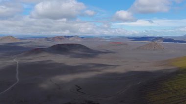 İzlanda 'nın volkanik arazisinin havadan görünüşü yosun kaplı tepeler, tepeler ve mavi gökyüzünün altındaki uzak dağlara uzanan düz bir düzlük..
