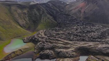 İzlanda 'nın volkanik arazisinin yavaş, engebeli bir havası. Karanlık lav tarlaları, dingin bir göl ve çok renkli mineral zengini dağlar..