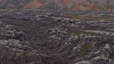 Tırtıklı yosunlar, Landmannalaugar, İzlanda 'daki lav tarlalarını ve renkli ryolite dağlarını kapladı. Yürüyüşçülerin dolambaçlı bir toprak yolda ilerlemesi,.