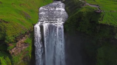 İzlanda 'daki yemyeşil bir vadinin havadan görünüşü şelaleye dökülen bir nehrin taşlı çıkıntılar ve canlı bitki örtüsüyle çevrili olması..