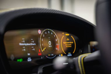 Porsche 911 'i kapatın. GT3 dijital ekranı takometre, hız göstergesi ve göstergeleri gösteriyor. Sarı dikişli direksiyon kısmen görünür..