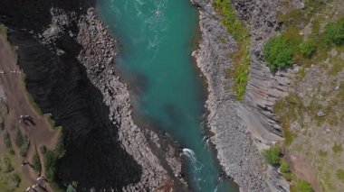 İzlanda 'daki Studlagil Kanyonu' nun hava manzarasında bazalt sütunlar, turkuaz bir nehir ve yeşillik yer alıyor. Pürüzsüz kamera hareketi peyzajı ortaya çıkarır.