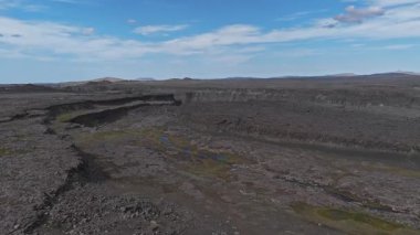 İzlanda 'da volkanik bir arazinin havasını süpüren bazaltik kaya, dik kanyon duvarları, yeşil bitki örtüsü ve parlak mavi bir gökyüzü..