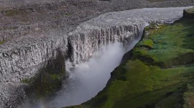 İzlanda 'daki Dettifoss şelalesi yükselen sis, engebeli arazi ve yeşil yosunlarla dolu bir kanyona dalıyor. Suyun hareketi dinamik ve kuvvetlidir..