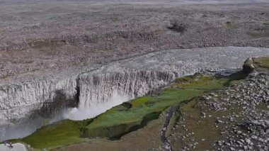 İzlanda 'daki Dettifoss şelalesinin hava manzarası, sürekli hareket halinde olan güçlü çağlayan su, sis, kayalık arazi ve yeşil yosunları gösteriyor..
