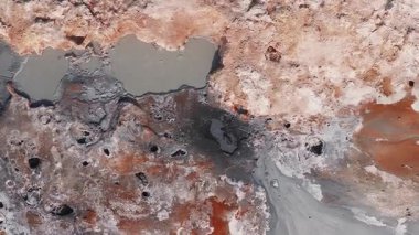 İzlanda 'da canlı bir jeotermal alanın havadan görünüşü. Kırmızı, turuncu ve beyaz arazi, buharlaşan bacalar ve hareketli gri çamur havuzları..