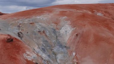 Kerlingarfjoll ve Studlagil Kanyonu 'nun havadan görünüşü - İzlanda' daki engebeli kırmızı tepeler, karlı bölgelerle kesişiyor. Kamera bulutlu bir gökyüzünün altında arazide süzülür..