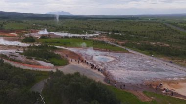 İzlanda 'da kaynayan gayzerler, kaplıcalar, yemyeşil, dolambaçlı yollar ve yolda yürüyen ziyaretçilerle dolu bir jeotermal alan..