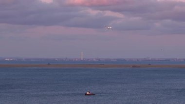 Günbatımında Kopenhag 'ın sakin bir hava manzarası Öresund Boğazı' ndan bir uçağın inişini gösteriyor. Yatları, rüzgar türbinleri ve endüstriyel binaları var..