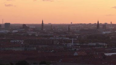 Kopenhag 'ın günbatımındaki hava görüntüsü, Kopenhag Elektrik Santrali, şehir binaları ve parlayan şehir manzarası boyunca geniş çaplı bir hareket..