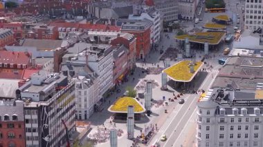 Kopenhag, Danimarka 'nın hava manzarası, Norreport metro istasyonu modern mimarisini, yeşil çatıları, hareket halindeki araçları, bisikletleri ve yayaları canlı şehir ortamında gösteriyor..