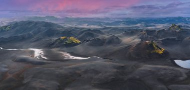 İzlanda 'da karanlık kumları, yosunlu tepeleri, kraterleri ve parlak pembe ve mor günbatımı gökyüzünün altında beyaz bir nehri olan gerçeküstü bir volkanik arazi..