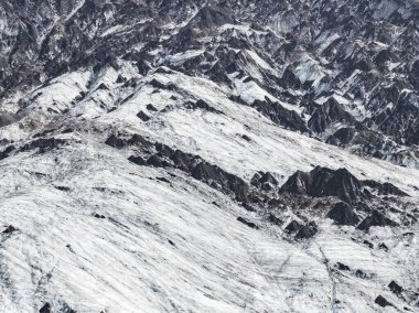 Keskin tepeler ve karanlık kaya oluşumlarıyla kaplı engebeli karlar. Dokunulmamış arazi İzlanda 'nın dramatik buzul manzarasını vurguluyor.