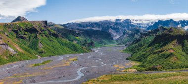 İzlanda 'daki siyah volkanik kumların üzerinde örülmüş bir nehrin havadan görünüşü, yeşil uçurumlar, karla kaplı dağlar ve berrak mavi gökyüzünün altındaki buzullar..