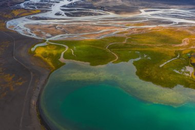 Turkuaz göl yemyeşil yosunlarla çevrili. Buzul nehirleri ve dereleri İzlanda 'nın dinamik ovalarında sallanıyor..