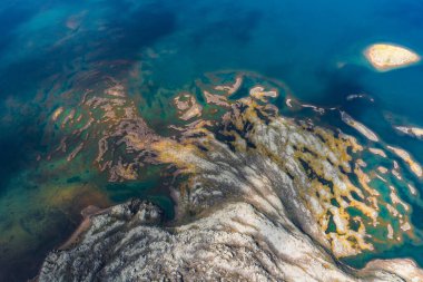 İzlanda 'nın sağ üst köşesinde küçük bir adanın yer aldığı, alg ve minerallerin altın ve yeşil desenli derin mavi suların hava manzarası..