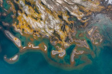 İzlanda 'nın kayalık arazi, canlı yosun, turkuaz sular ve doğal bir arazide dönen çökeltilerin yer aldığı kıyı şeridinin havadan görünüşü.