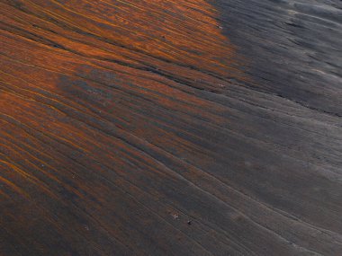 İzlanda 'da kıraç bir volkanik arazinin havadan görünüşü, parlak turuncu ve pas renginde desenlerle kaplı koyu renkli küller içeriyor..